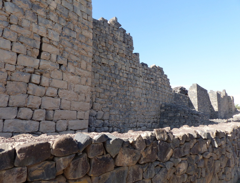 Malgré des remaniements sous les Byzantins, sous les Ottomans et jusqu’à l’époque contemporaine, la « forteresse bleue » conserve la structure d'un fort romain d'époque tardive. Il s’agit d’un camp presque carré de 76 x 72 m, à tours d'angle légèrement saillantes. Les murs atteignent une épaisseur de deux mètres. Des photographies aériennes prises en 1922 ont montré qu’il se superposait à un fort plus ancien et plus vaste, de structure proche des camps romains du siège de Massada (73 ap. J.-C.).
CC 4.0 Odysseum, photo F. Poli
Page à consulter :
Glossaire du Musée virtuel
Qasr al-Azraq, l’enceinte du fort.JPG