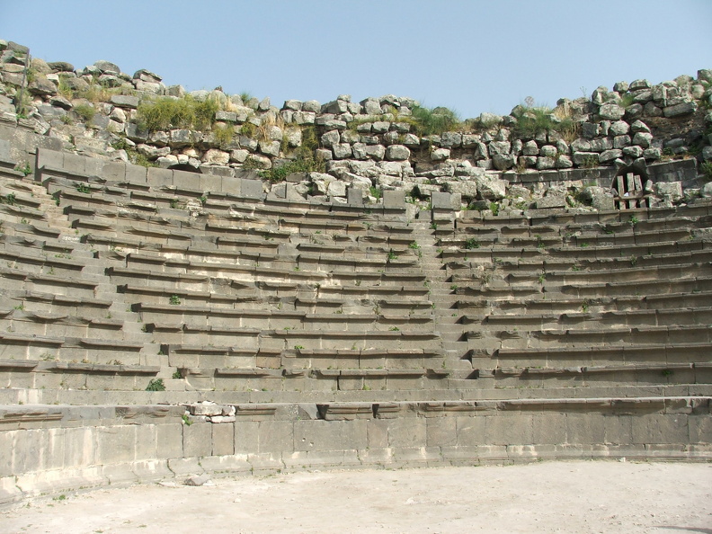 À la fin du Ier s. ap. J.-C. Gadara était devenue un centre de villégiature pour les riches Romains venus profiter des sources thermales d’eaux chaudes. La cité comptait alors deux théâtres qui leur offraient des spectacles. Les gradins de celui-ci, le plus petit, sont assez bien conservés. Il accueillait jusqu’à 3000 personnes et pouvait servir de lieu de réunion publique. Certains sièges sans doute réservés aux notables de la ville ont conservé leur dossier en pierre noire de basalte.
CC 4.0 Odysseum, photo F. Poli
Articles à consulter :
architecture du théâtre - glossaire du Musée virtuel
Umm Qeis, la cauea du théâtre ouest.JPG