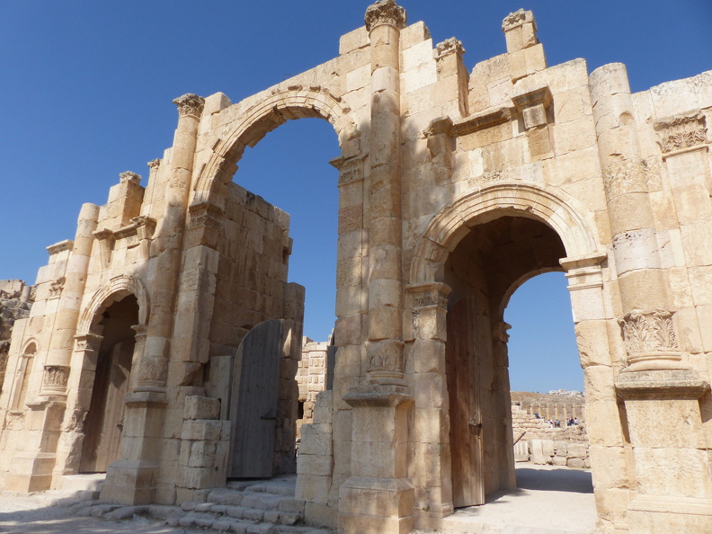 Cet emplacement marquait déjà l’entrée sud de la ville dès sa construction. On y a élevé une porte contemporaine de l’arc d’Hadrien, puisqu’elle s’inspire du même décor de bulbes d’acanthe à la base des colonnes. Au IVe s. ap. J.-C., la porte sud est intégrée à un mur d’enceinte de 3,5 km de périmètre, renforcé de tours carrées. Plusieurs portes perçaient le rempart, mais ne subsistent que celles du sud et du nord construites respectivement en l’honneur des empereurs Hadrien et Trajan.
CC 4.0 Odysseum, photo F. Poli
Articles à consulter :
les empereurs romains - glossaire du Musée virtuel
Jerash, la porte sud.JPG