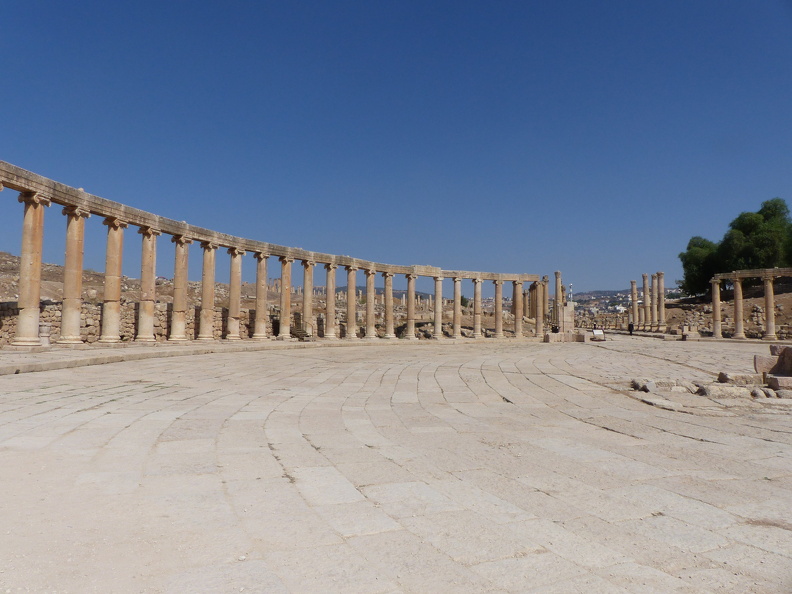 Considérée à tort comme le forum de la cité, cette place elliptique construite au début du IIe s. ap. J.-C. était un espace sacré avec en son centre un autel consacré au culte impérial. Elle permettait de relier avec élégance le sanctuaire de Zeus au cardo maximus. La place de 100 m de long est entourée de 56 colonnes aux chapiteaux doriques et corinthiens. La taille des dalles disposées de façon concentrique augmente à mesure que l’on s’éloigne du centre, renforçant l’impression de tourbillon.
CC 4.0 Odysseum, photo F. Poli
Article à consulter :
glossaire du Musée virtuel
Jerash, la place ovale.JPG