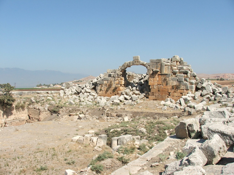 Des remparts encerclaient Apamée sur 7 km, en suivant les reliefs de la colline. Restaurés aux époques romaine et byzantine, ils s’élevaient jusqu’à 10 m de haut. Quatre portes assuraient l’accès à la ville. De la porte nord, encore visible, une route pavée conduisait jusqu’à Antioche (Turquie), l’une des autres villes de la tétrapole séleucide. Pour faire face aux offensives du roi perse sassanide Shapur Ier (240 - 272 ap. J.-C.), les remparts furent renforcés d’une cinquantaine de tours.
CC 4.0 Odysseum, photo F. Poli
Article à consulter : glossaire du musée virtuel
Apamée, la porte nord ou porte d’Antioche.JPG
