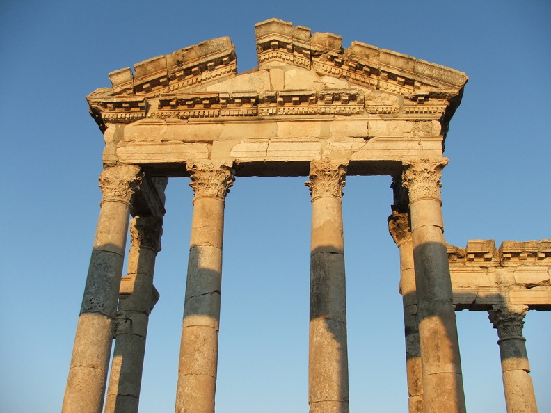 Le Tychéion orné d’un fronton était dédié à la déesse féminine Tyché protectrice de la cité. Son temple était probablement à l’emplacement d’une fontaine publique. Plus à l’ouest se trouvait l’imposant temple de Zeus Bêlos, dieu cosmique et oraculaire. L’empereur Septime-Sévère consulta l’oracle deux fois. Le culte fut maintenu jusqu’à la destruction du sanctuaire en 386 ap. J.-C. sur ordre de l’évêque Marcel d’Apamée en application des premiers édits de l’empereur Constance II (357 ap. J.-C.)
CC 4.0 Odysseum, photo F. Poli
Articles à consulter : Zeus - les empereurs romains - glossaire du musée virtuel
Apamée, le Tychéion, détail.JPG