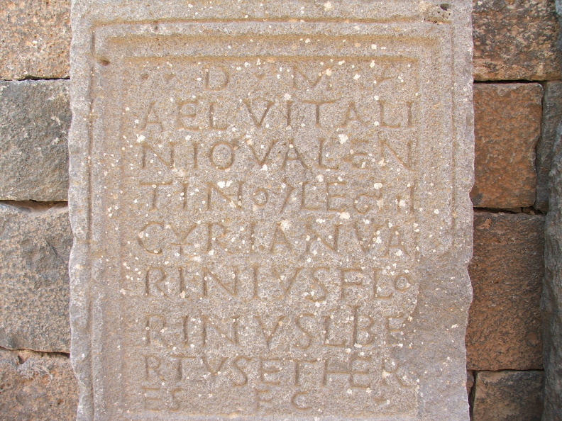 On a retrouvé à Bosra des inscriptions en nabatéen et surtout en langue grecque. Mais le latin était employé par les soldats romains ainsi que dans les formulaires des épitaphes. La stèle funéraire (AE 1965, 26) est dédiée à Aelius Vitalinus Valentinus, centurion de la légion IIIe Cyrénaïque. Son affranchi (libertus) et héritier (heres) en est le dédicant. Cette légion basée dans un vaste camp au nord de Bosra assurait une présence militaire romaine en patrouillant dans la Province d’Arabie.
CC 4.0 Odysseum, photo F. Poli
Article à consulter :
Glossaire du musée virtuel
Bosra, stèle funéraire d’un centurion romain.JPG