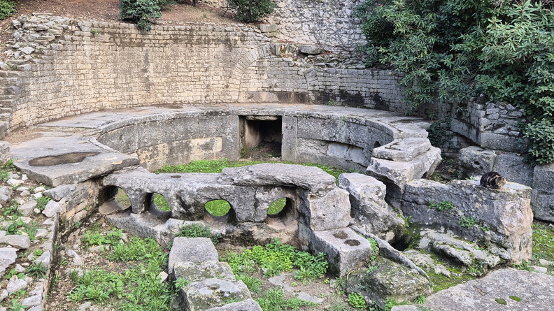 Le castellum aquae (château d’eau), réservoir d’eau et bassin de distribution, date du milieu du Ier s. ap. J.-C. Il sécurisait en période de sécheresse l’approvisionnement en eau, en complément des eaux de la source de Nemausus et des nappes phréatiques. Une large ouverture permettait l’arrivée de l’eau de l’aqueduc. Le bassin circulaire de 6 m de diamètre est percé de dix ouvertures qui étaient prolongées de tuyaux en plomb destinés à acheminer l’eau dans les différents quartiers de la ville.
Photos CC 4.0 Odysseum, classe de P. Cochet Terrasson 2025
Articles à consulter :
L’eau dans l’Antiquité - Les Romains et l’eau - Glossaire du musée virtuel
Nîmes, bassin du castellum aquae.jpg